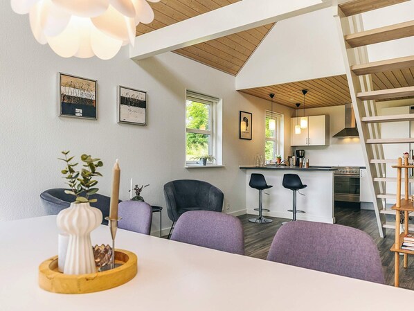 Una cocina moderna con techo de madera, un comedor con sillas moradas y una escalera.