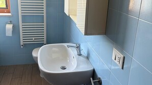 Une salle de bain avec un lavabo blanc, un porte-serviettes et un miroir.