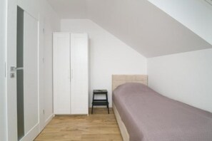 Eine kleine Einzimmerwohnung mit einem Bett, einem Kleiderschrank und einem kleinen Tisch.