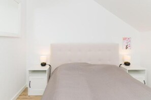 A bedroom with a bed, nightstands, and a wall-mounted picture.