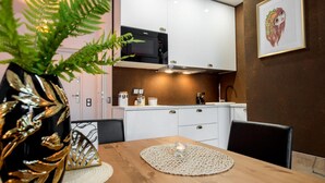 A modern kitchen with white cabinets, a black microwave, and a dining area with a wooden table and chairs.