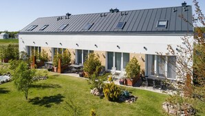 A modern building with a flat roof, large windows, and outdoor seating area.