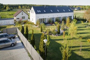 Ein modernes Haus mit Satteldach, einem umzäunten Garten und einem Auto auf der Auffahrt.