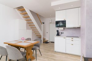 A modern kitchen with white cabinets, a microwave, and a coffee machine.