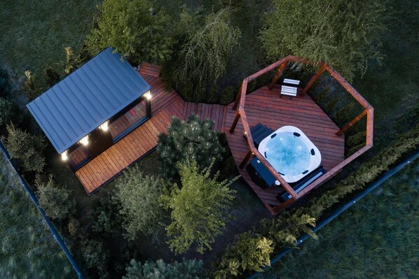 A hot tub on a wooden deck with a metal roof structure nearby.