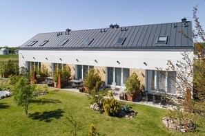 A modern building with a flat roof, large windows, and outdoor seating area.