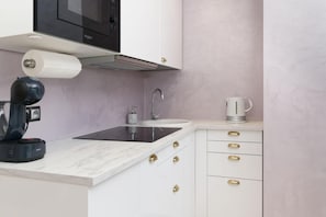 Een moderne keuken met een ingebouwde magnetron, een spoelbak en een waterkoker op het aanrecht.
