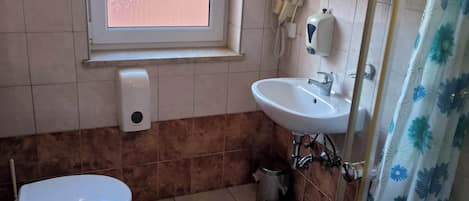 A bathroom with a toilet, sink, and window.