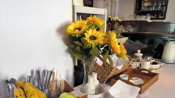 Une table de petit-déjeuner avec des fruits, du pain et un vase rempli de tournesols.