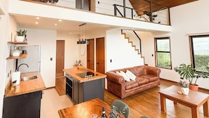 En modern lägenhet i loftstil med kök, matplats och vardagsrum.