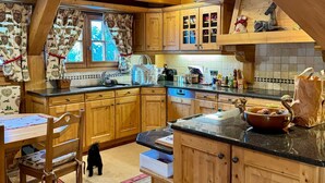 Une cuisine rustique avec des meubles en bois, une cheminée en pierre et un coin repas comprenant une table et des chaises.