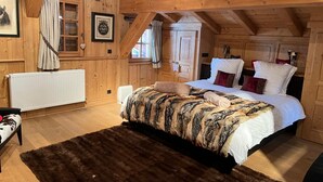 Une chambre confortable dans un chalet en bois, avec un grand lit, un radiateur et une fenêtre avec des rideaux.