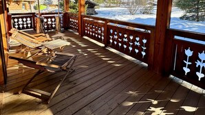 Une terrasse en bois avec des chaises longues et une vue sur des montagnes enneigées.