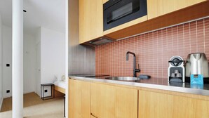 A modern kitchen with wooden cabinets, a stainless steel sink, and a microwave. - Beautiful Apartment 1br/3p - Marais/republique (Paris)