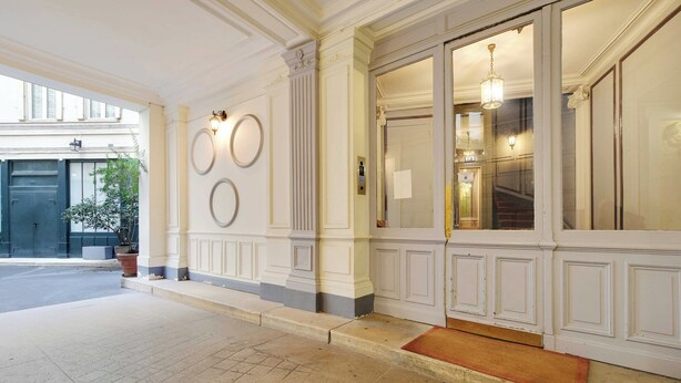A hotel entrance with a tiled floor, a potted plant, and a red mat at the door. - Beautiful Apartment 1br/3p - Marais/republique (Paris)