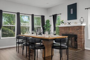 A dining area with a long wooden table, black chairs, and a brick fireplace. - Spacious 4BR Family Home with Pool, Hot Tub & Games (San Antonio)