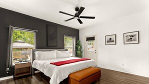 A bedroom with a bed, a bench, a ceiling fan, and a door.