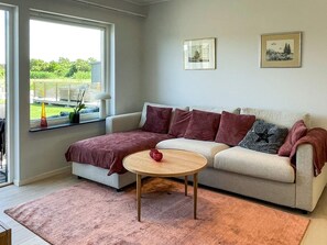 A living room with a sofa, a coffee table, and a window with a view of greenery. - 5 Star Holiday Home in Morbylanga (Morbylanga)