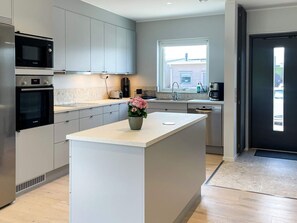 A modern kitchen with a central island, built-in appliances, and a window providing natural light.