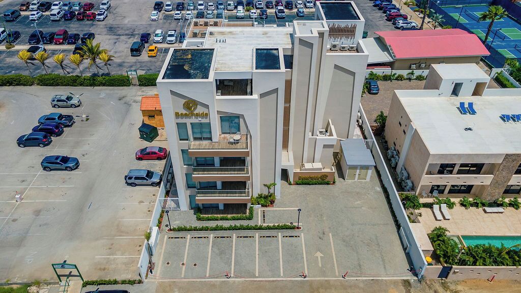 Un hotel moderno con un patio central, múltiples estacionamientos y una zona de piscina.