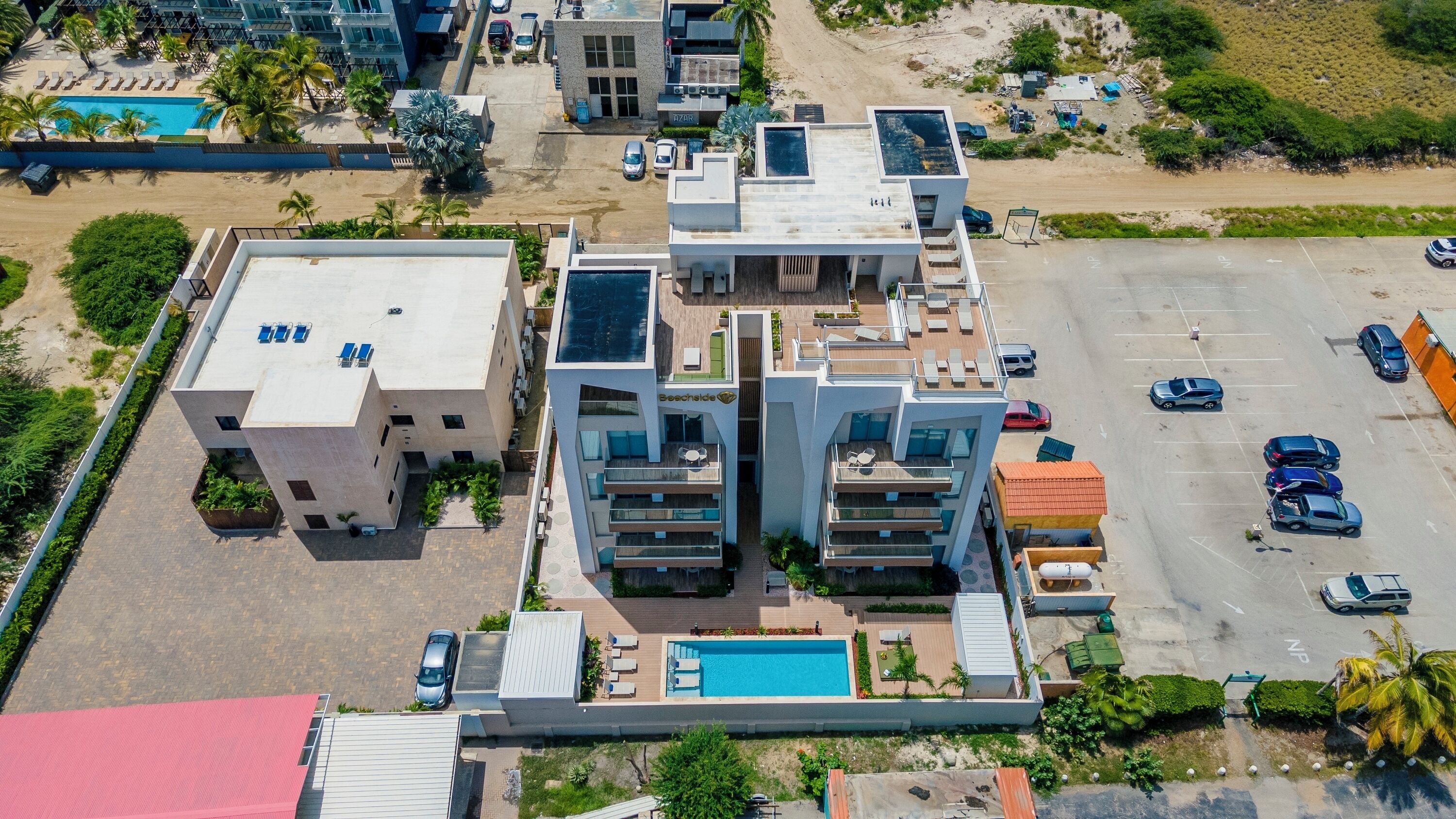 Ein moderner Hotelkomplex mit mehreren Gebäuden, einem Schwimmbad und einem Parkplatz.