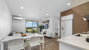 Cocina moderna con armarios blancos, horno empotrado y un ventanal con vistas al exterior.