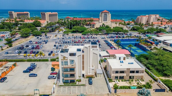 Un hotel con un patio central, varios estacionamientos y vista al océano.