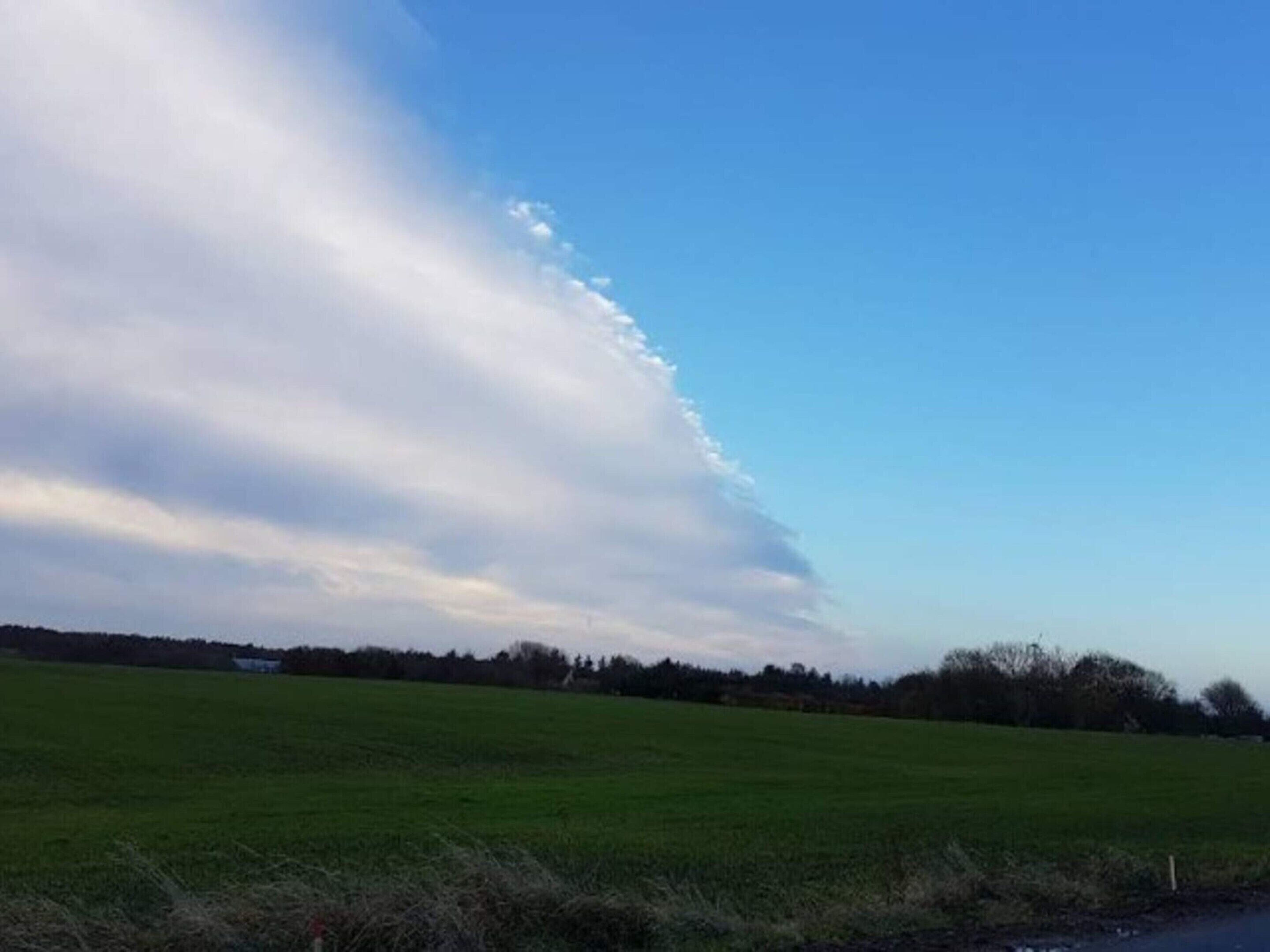 A wide-open field with a clear sky and a few clouds.