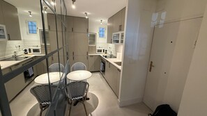 A modern kitchen with a round dining table, built-in appliances, and a glass partition. - Nestled in the heart of Madrid’s most exclusive neighborhood, this charming basement apartment offers a perfect blend of style, comfort, and unbeatable location. Situated in Salamanca, you'll be steps away from high-end boutiques, gourmet restaurants (MADRID)