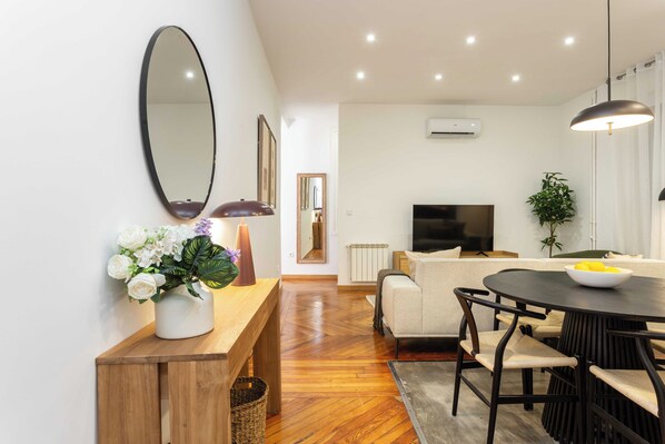 A modern living room with a wooden bench, a round dining table, and a television.