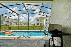 Una piscina exterior cubierta con una parrilla y zona de descanso.