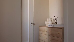 A hallway with a wooden dresser, a white door, and a small rug. - The Brick Studio in Los Feliz (Los Angeles)