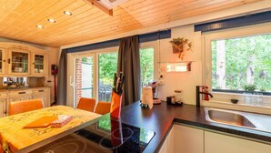 A modern kitchen with a dining area, wooden ceiling, and large windows. - Chalet in Hastiere Near Castle (Hastiere)