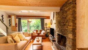 A cozy living room with a stone fireplace, wooden flooring, and a sofa with cushions. - Chalet in Hastiere Near Castle (Hastiere)