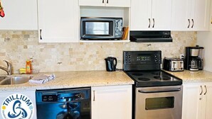 A kitchen with white cabinets, a microwave, a stove, a dishwasher, and a coffee maker. - Blue Mountain Suites (Blue Mountain)