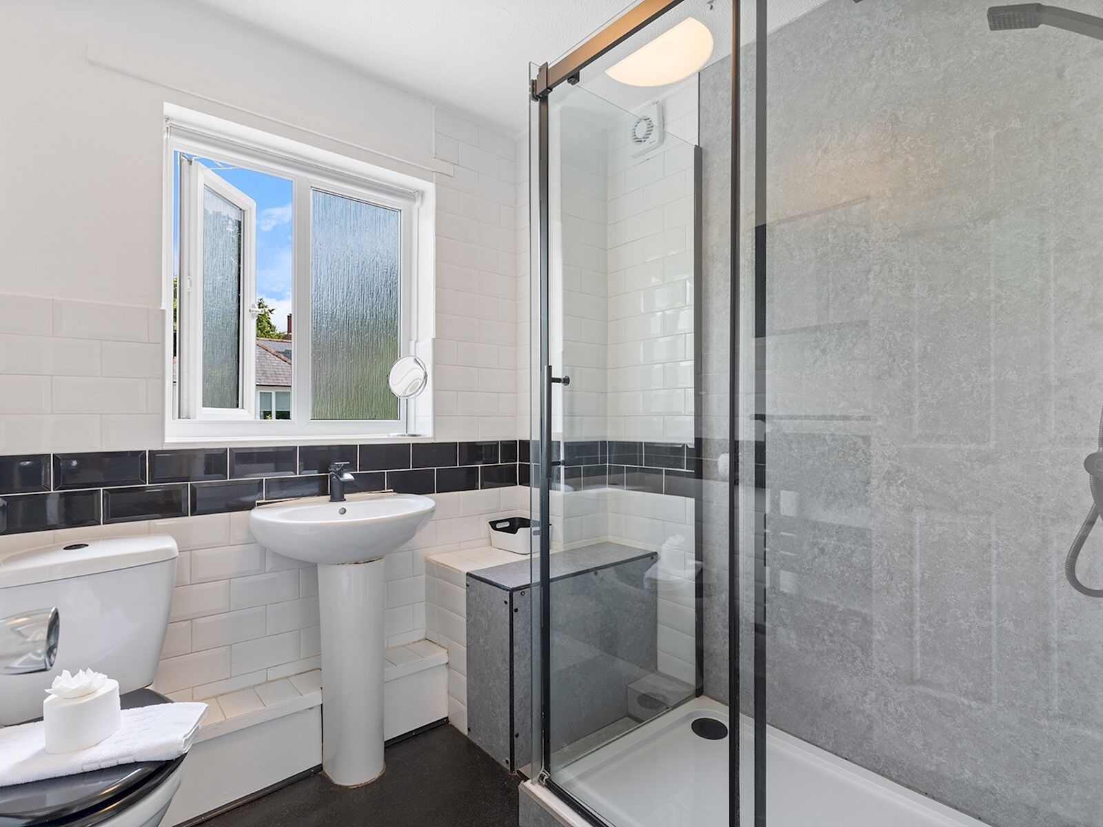Une salle de bain moderne avec une douche à parois de verre, un lavabo blanc et des toilettes.