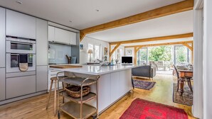 Een moderne keuken met een centraal eiland, houten balken en uitzicht op een eetgedeelte.