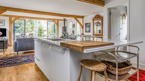Een moderne keuken met een groot eiland, houten balken en uitzicht op het buiten.