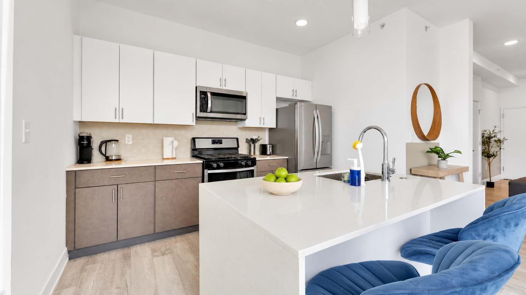A modern kitchen with white cabinets, a stainless steel refrigerator, a microwave, and a stove.