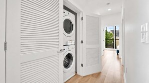 A laundry room with two washing machines and a door leading to a balcony. - Posh 3BR Flat by Liberty Bell | Hosts Group of 6 (Philadelphia)