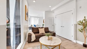 A modern living room with a sofa, a coffee table, and a potted plant. - Posh 3BR Flat by Liberty Bell | Hosts Group of 6 (Philadelphia)