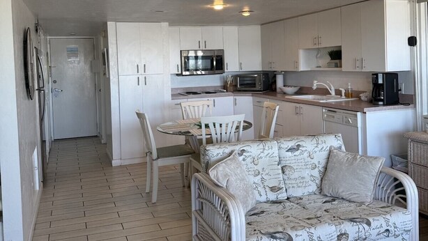 A modern kitchen with white cabinets, a microwave, and a coffee maker.