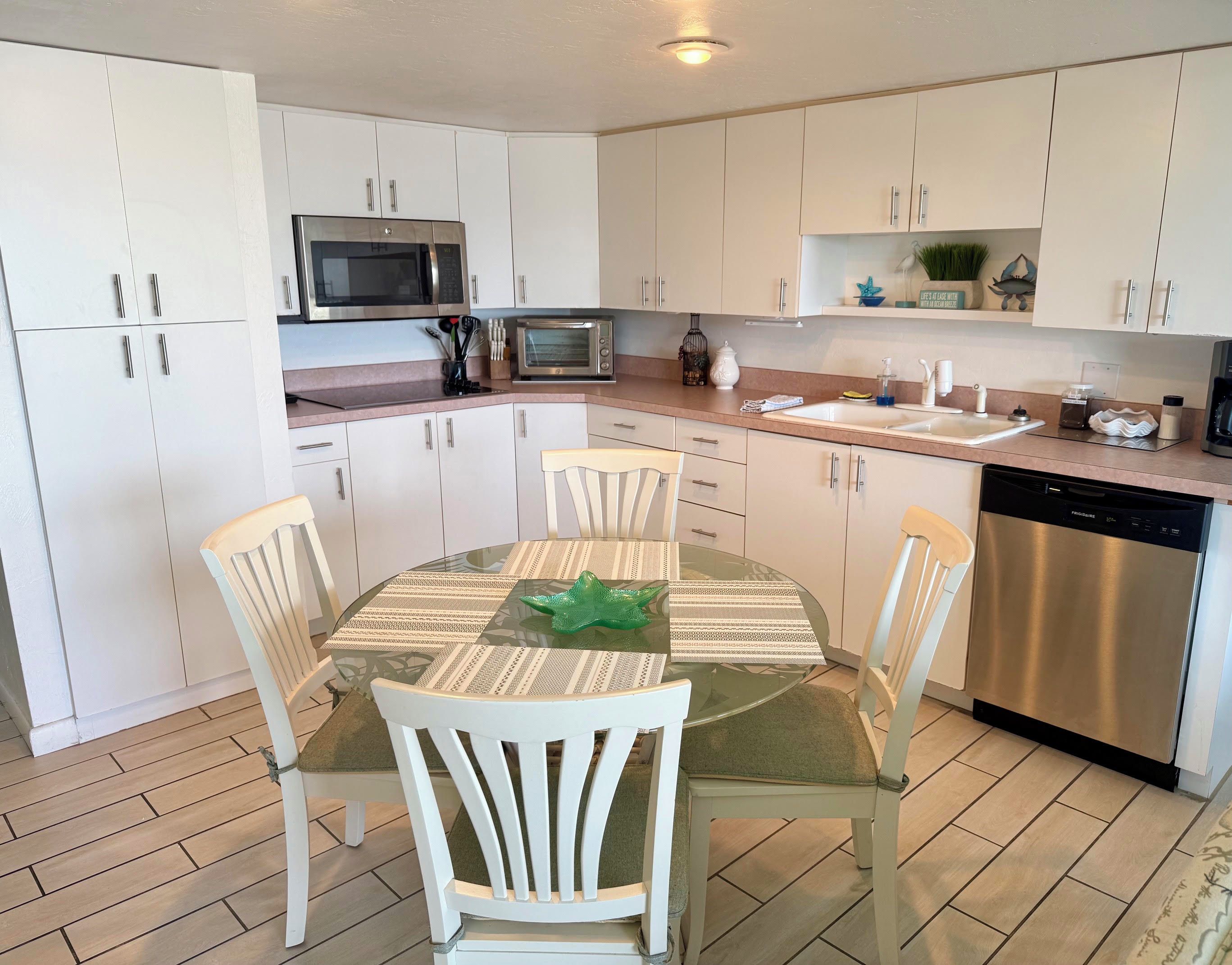 Een moderne keuken met witte kasten, roestvrijstalen apparatuur en een ronde eettafel met stoelen.