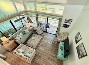 A spacious living area with a large window, a sofa, a coffee table, and a patterned armchair.