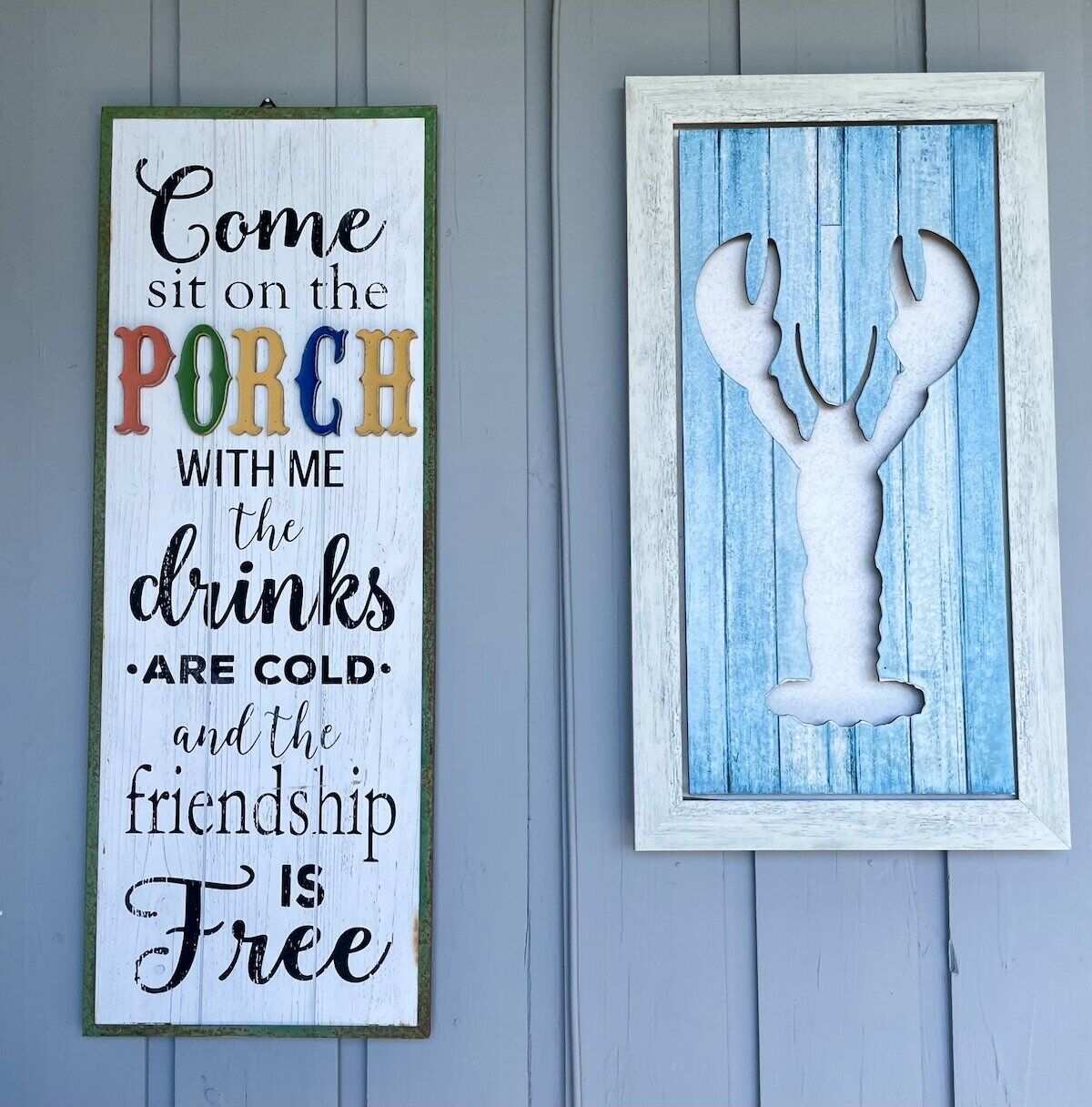 A wall with two decorative signs: one with a colorful text inviting someone to sit on the porch, and another with a white silhouette of a lobster.
