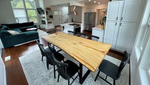 A modern kitchen with white cabinets, a wooden dining table, and black chairs.