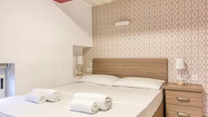 A hotel room with a large bed, a wooden headboard, a bedside table with a lamp, and a patterned wall. - Charming, designer 1 bedroom Valletta Loft (Valletta)