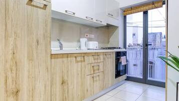 Une cuisine moderne avec des meubles en bois, un plan de travail blanc et une vue sur la ville grâce à une grande fenêtre.