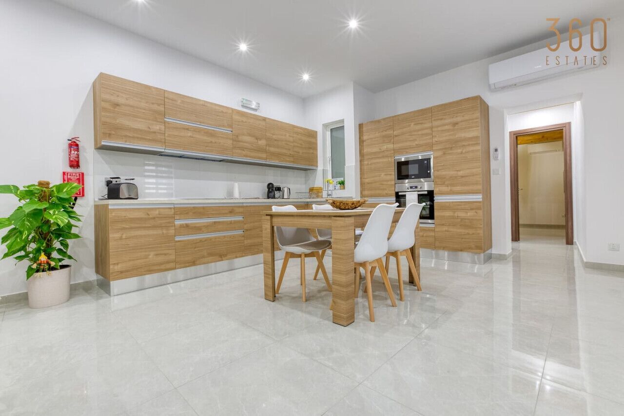 A modern kitchen with wooden cabinets, a dining table, and chairs.