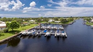 Una marina con barcos amarrados a lo largo de un canal, rodeada de vegetación y edificios.